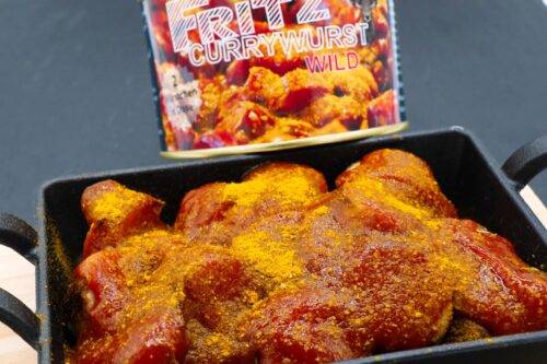Eine Wildwurst von Fritz Currywurst, serviert mit würziger Soße und Currypulver – ein Genuss für Liebhaber herzhafter Wildspezialitäten.